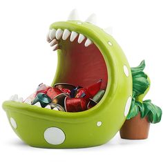 a green dinosaur shaped planter filled with assorted candy and candies in it's mouth