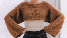 a woman wearing a brown sweater and black skirt