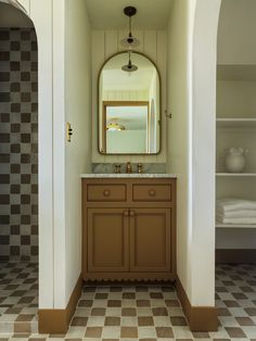 a bathroom with a checkered floor and an oval mirror