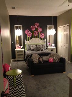 a bedroom decorated in black and white with pink flowers on the headboard, dressers, mirror, and bed