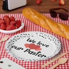 there is a paper plate with the words we love our pastor on it next to some strawberries