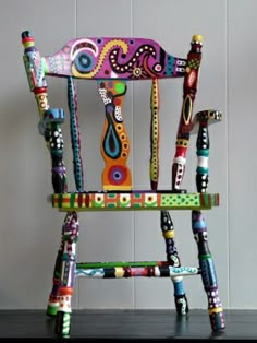 a colorful wooden rocking chair sitting on top of a hard wood floor next to a wall