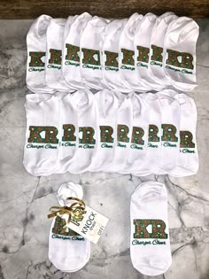 six pairs of white socks with green and gold letters on them sitting on a marble surface