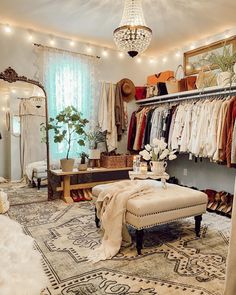 an image of a walk in closet with clothes on racks and chandelier hanging from the ceiling