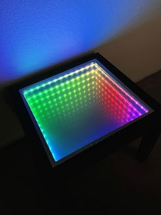 a square light up table in the dark with blue and green lights on it's sides