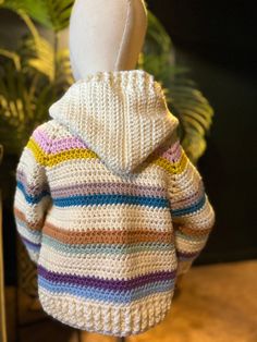 a crocheted sweater with a hood on top of a mannequin's head