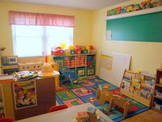 a child's playroom with toys and books on the floor in front of a window