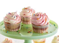 three cupcakes with pink frosting and sprinkles on a plate