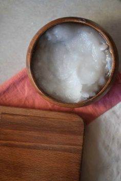 a wooden bowl filled with ice sitting on top of a pink napkin next to a wooden box