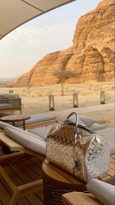 a bag sitting on top of a wooden table next to some chairs and an umbrella