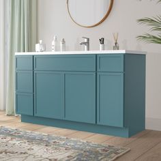 a bathroom vanity with blue cabinets and white counter tops, in front of a large mirror