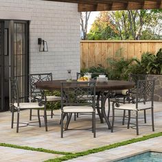 an outdoor dining table and chairs near a pool