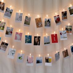 a string of lights is hanging from a wall with pictures on it and candles in the middle