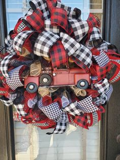 a red truck wreath with black and white plaid ribbon on the front door for christmas