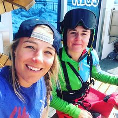 two women sitting on a bench wearing skis