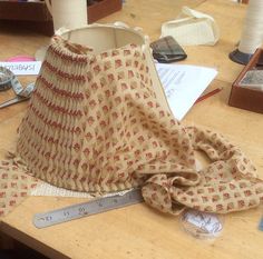 a lamp shade sitting on top of a wooden table next to a measuring tape and thread