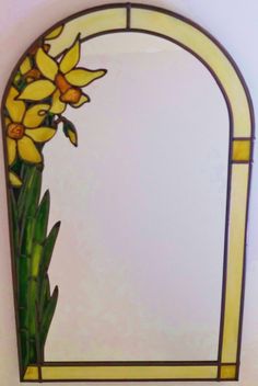 a stained glass window with yellow flowers on it's side and green stems in the foreground