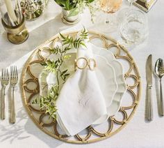 a place setting with napkins, silverware and flowers on a white table cloth