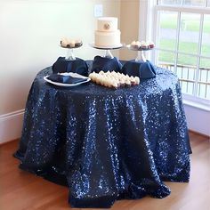 a table with blue sequins on it and two cakes sitting on top of it