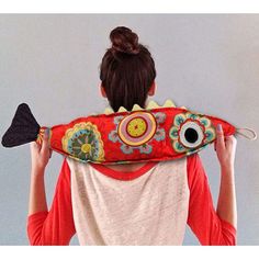 a woman is holding up a red pillow with an eyeball on it's back