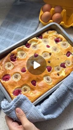 a person holding a pan filled with fruit and banana bread on top of a blue towel