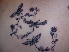 the back of a woman's shoulder with dragon tattoos and name written in cursive writing