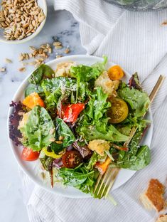 a white plate topped with a salad next to bread