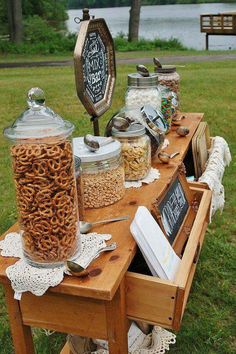 a wooden table topped with lots of different types of food and drink bottles on top of it