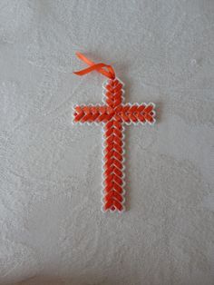 an orange cross on a white cloth with a red ribbon hanging from it's center