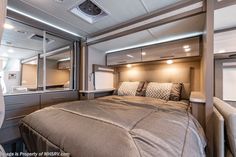 a bedroom with a bed, dresser and mirror in the back wall is lit by recessed lights