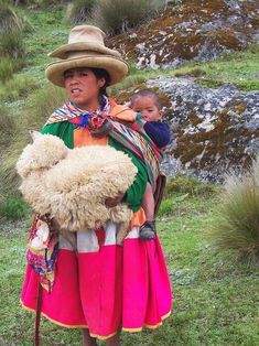 a woman with a baby in her arms wearing a hat and holding a stuffed animal