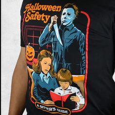 a man wearing a halloween safety t - shirt while holding a knife and reading a book