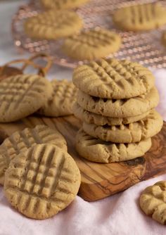 several peanut butter cookies stacked on top of each other next to a wooden cutting board