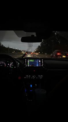 the dashboard of a car at night with lights on and cars driving in the background