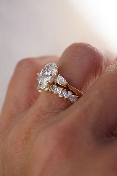 a person's hand holding an engagement ring with three stones on it and the other side