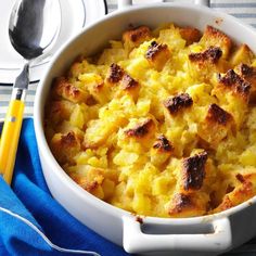 a casserole dish with bread and potatoes in it on a blue napkin next to a yellow fork