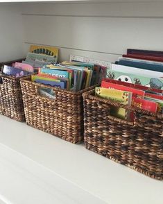 three wicker baskets filled with books sit on a shelf in a children's room