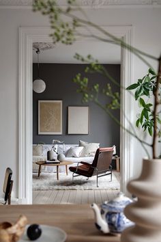 a living room filled with furniture next to a wooden table and vases on top of a hard wood floor