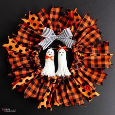 a wreath with two ghost decorations on it