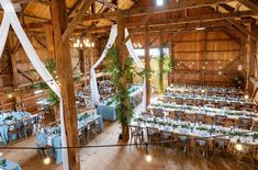 the inside of a barn with tables and chairs set up for a formal function in blue linens