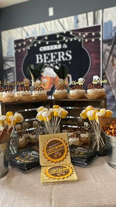 a table topped with cupcakes and other desserts next to a sign that says beers