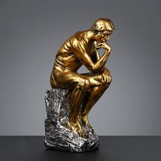 a bronze statue of a man sitting on top of a rock