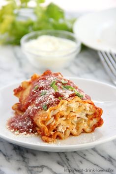 a white plate topped with lasagna covered in sauce next to a glass of wine