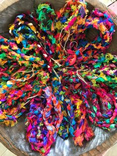 a wooden bowl filled with lots of colorful yarn