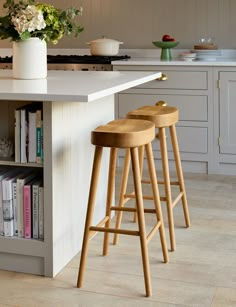 two wooden stools sit in front of an island with bookshelves on it