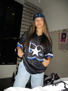 a woman standing next to a bed wearing a black and blue shirt with stars on it