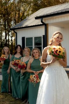 a bride and her bridesmaids in front of a small white building holding bouquets