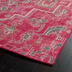 a red rug with an intricate design on the top and bottom, sitting on a wooden floor