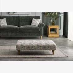 a living room with a gray couch and footstool next to a coffee table