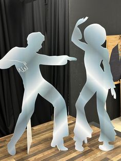 two paper cutouts of people dancing on a wooden table